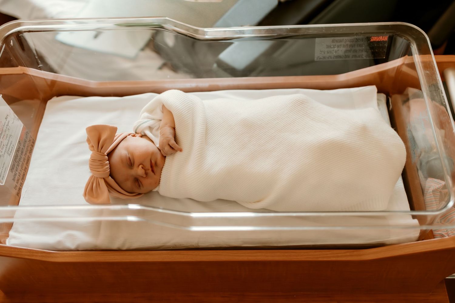 Newborn rests peacefully in hospital bassinet.