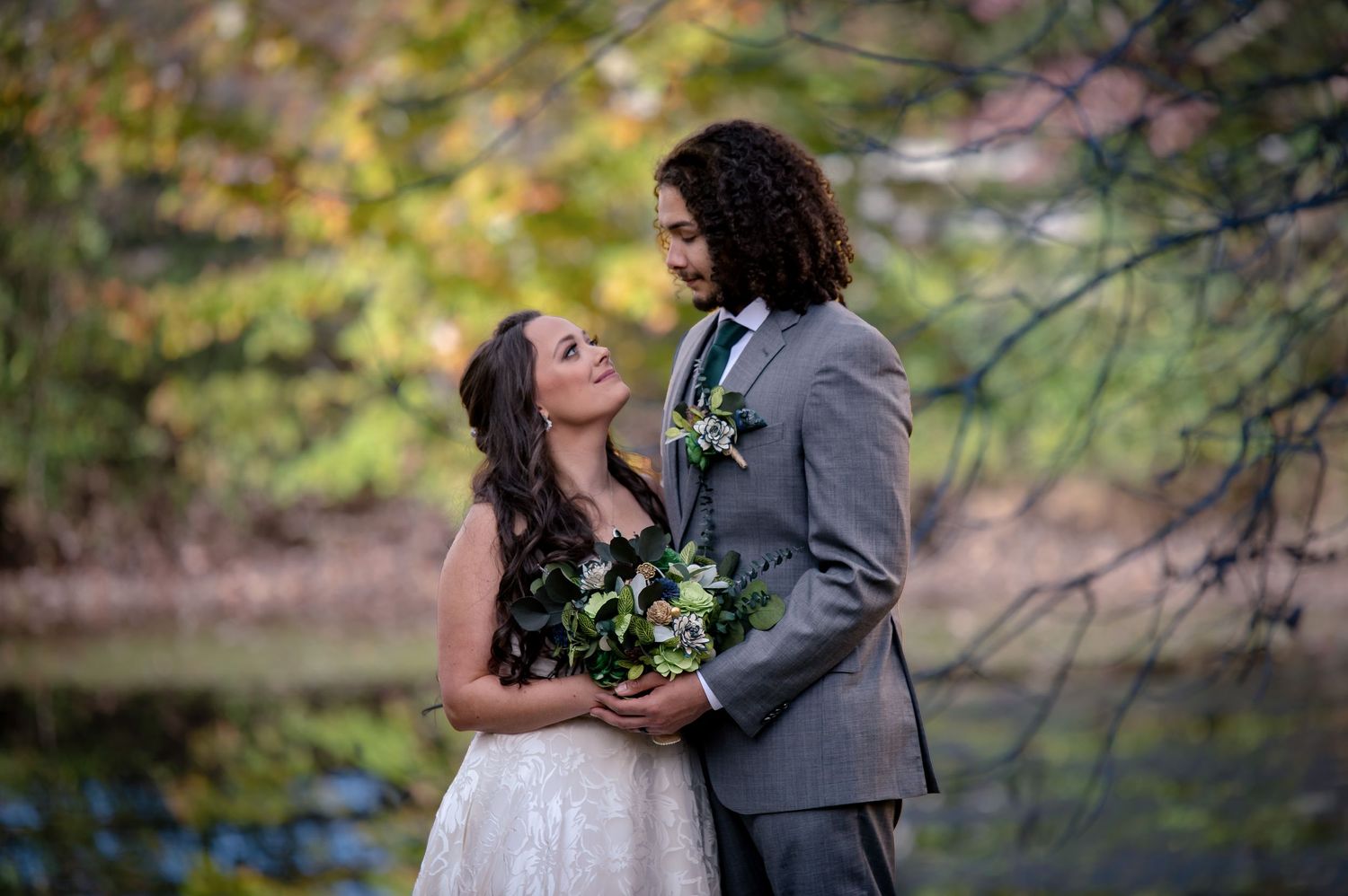 A romantic wedding portrait among fall foliage with natural lighting.