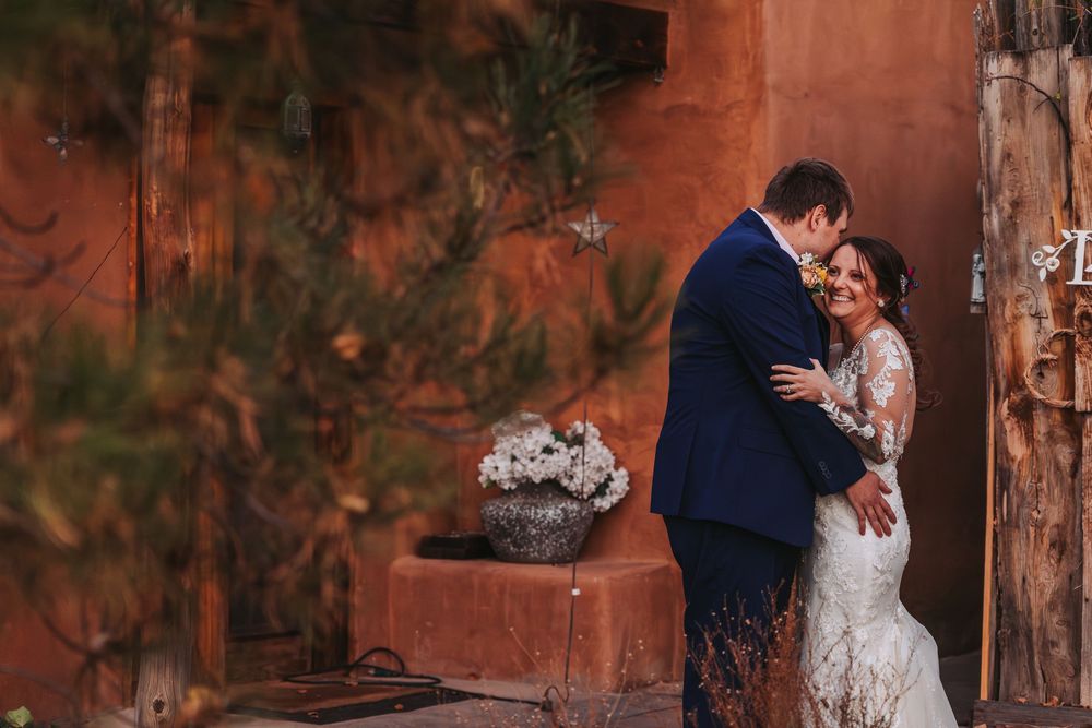 A couple shares romantic moments in a rustic outdoor setting with glowing red rock formations in the background.
