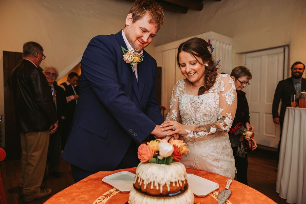 Wedding guests gather around a chocolate cake during the reception celebration.