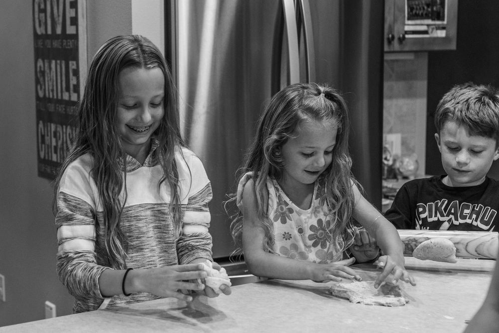 Children sitting at desks work diligently on writing or drawing activities in a classroom setting.