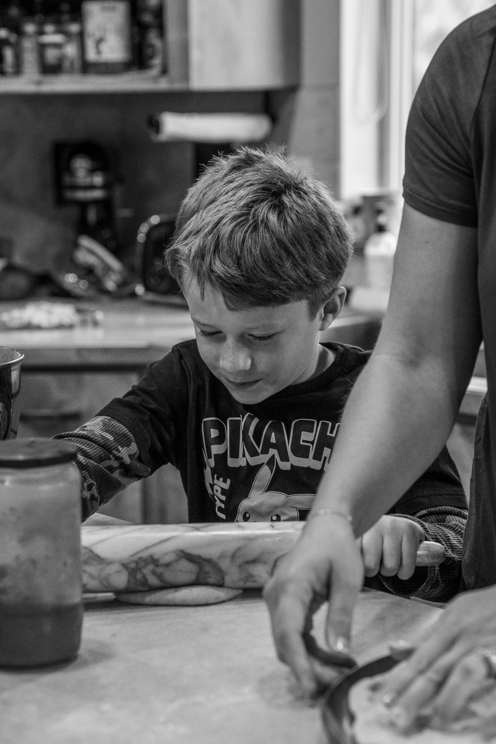 A black and white photo series showing hands working with dough or clay on a table surface.