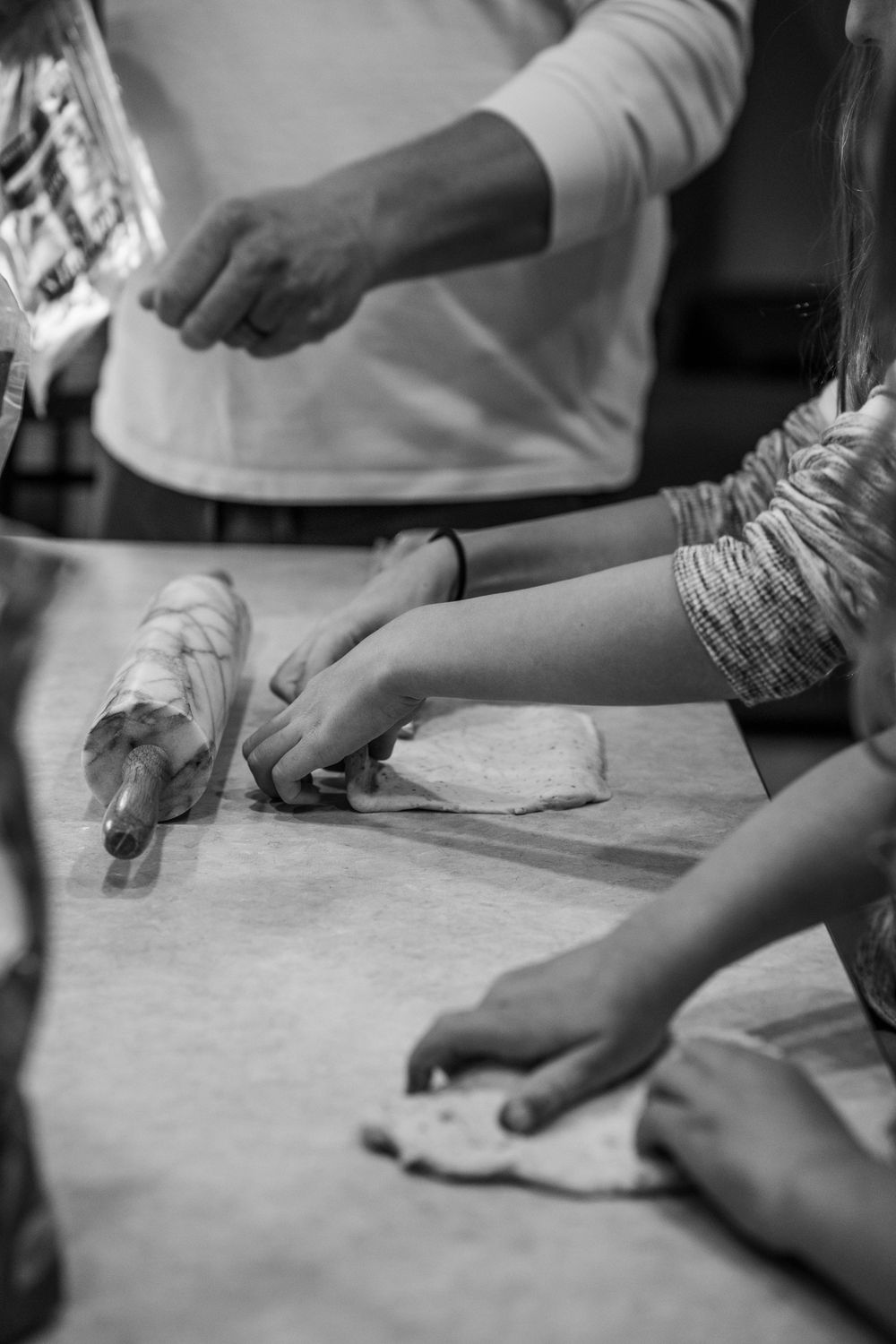 Close-up black and white shots of hands working with dough on a floured surface in sequence.