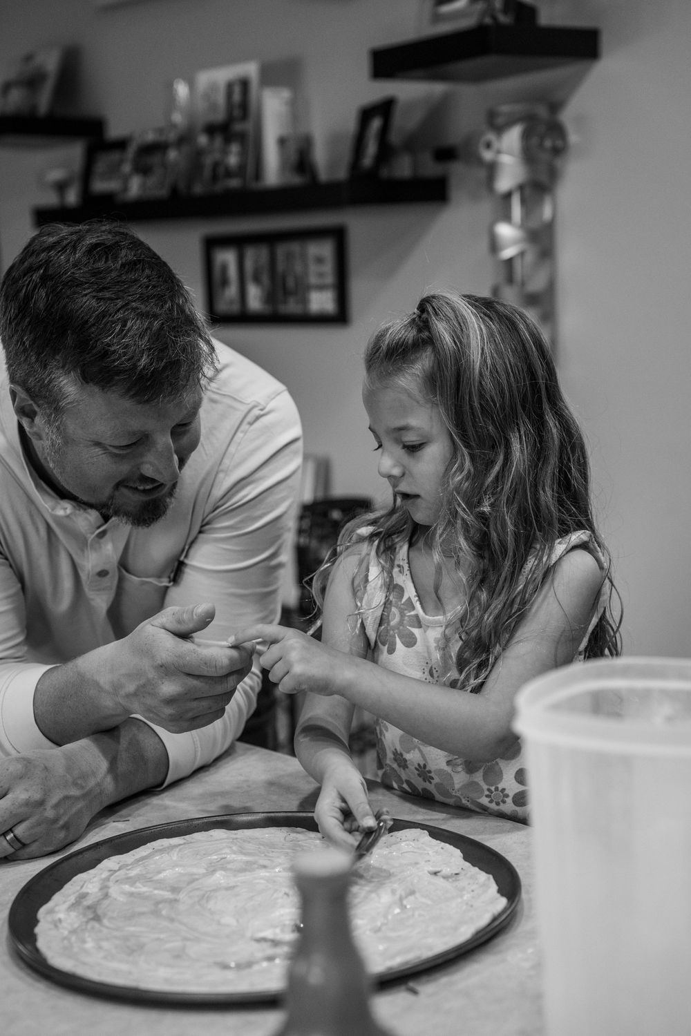 A sequence of black and white photos showing a parent and child playfully eating whipped cream from a plate.