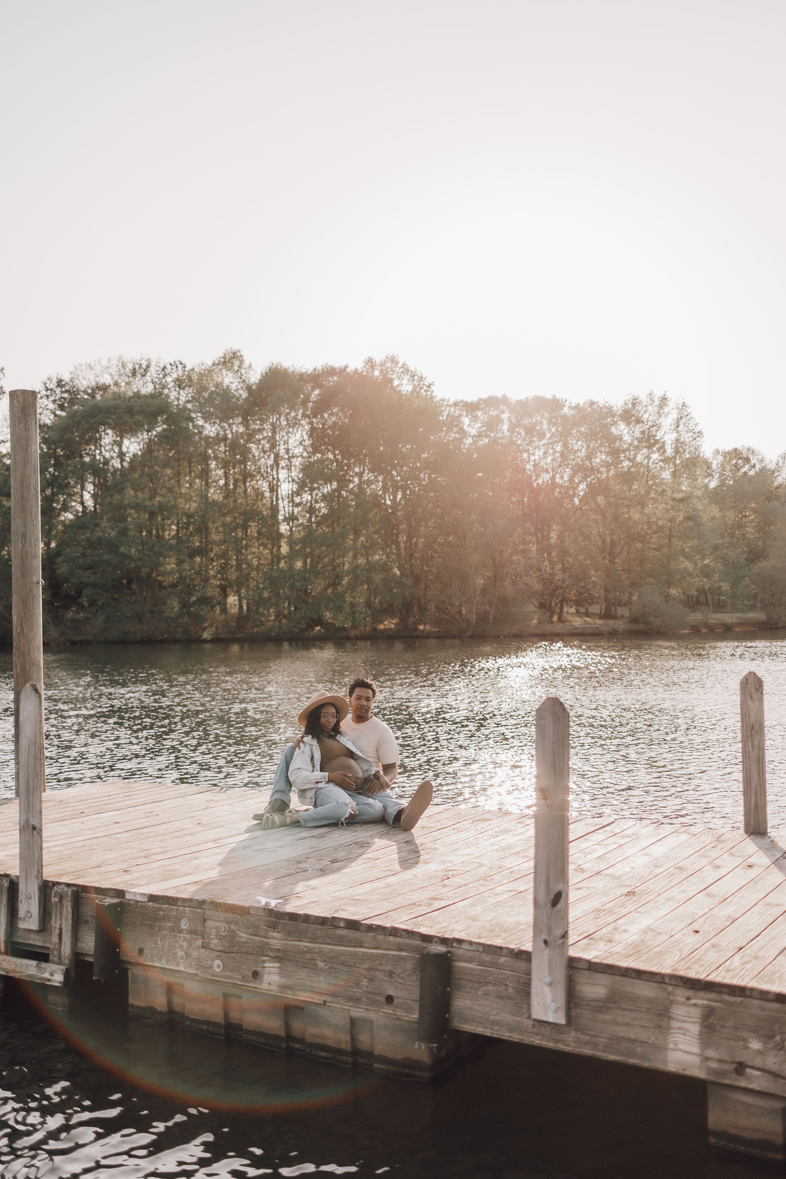 Romantic sunset scene at a wooden dock overlooking a serene lake with golden light reflecting on the water.