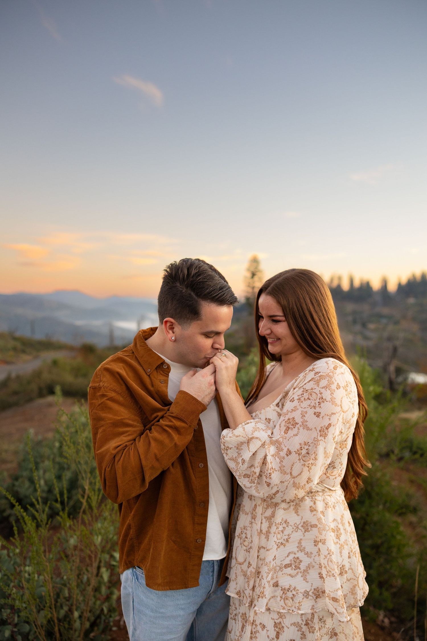 A couple shares an intimate moment at sunset in a scenic mountain landscape.