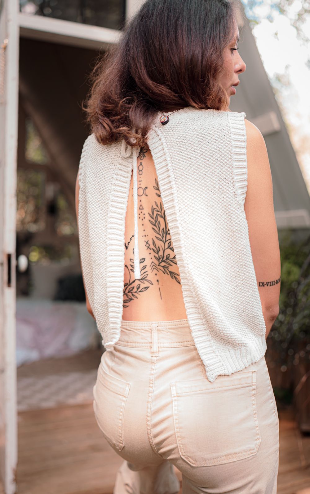 Back view of white sleeveless dress with floral tattoo detail visible through open back design.