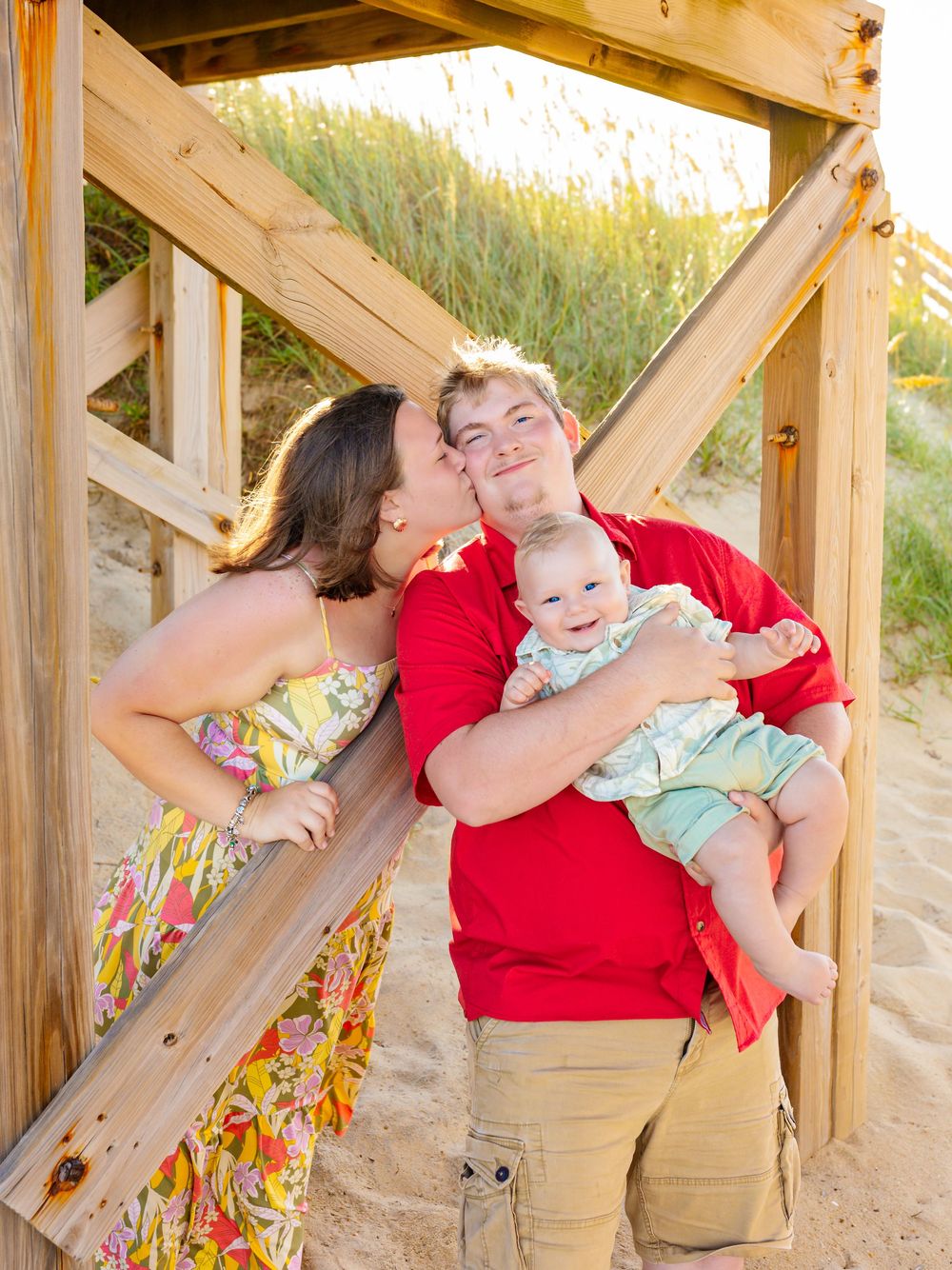 Family shares tender moments on wooden beach boardwalk during sunset photoshoot.