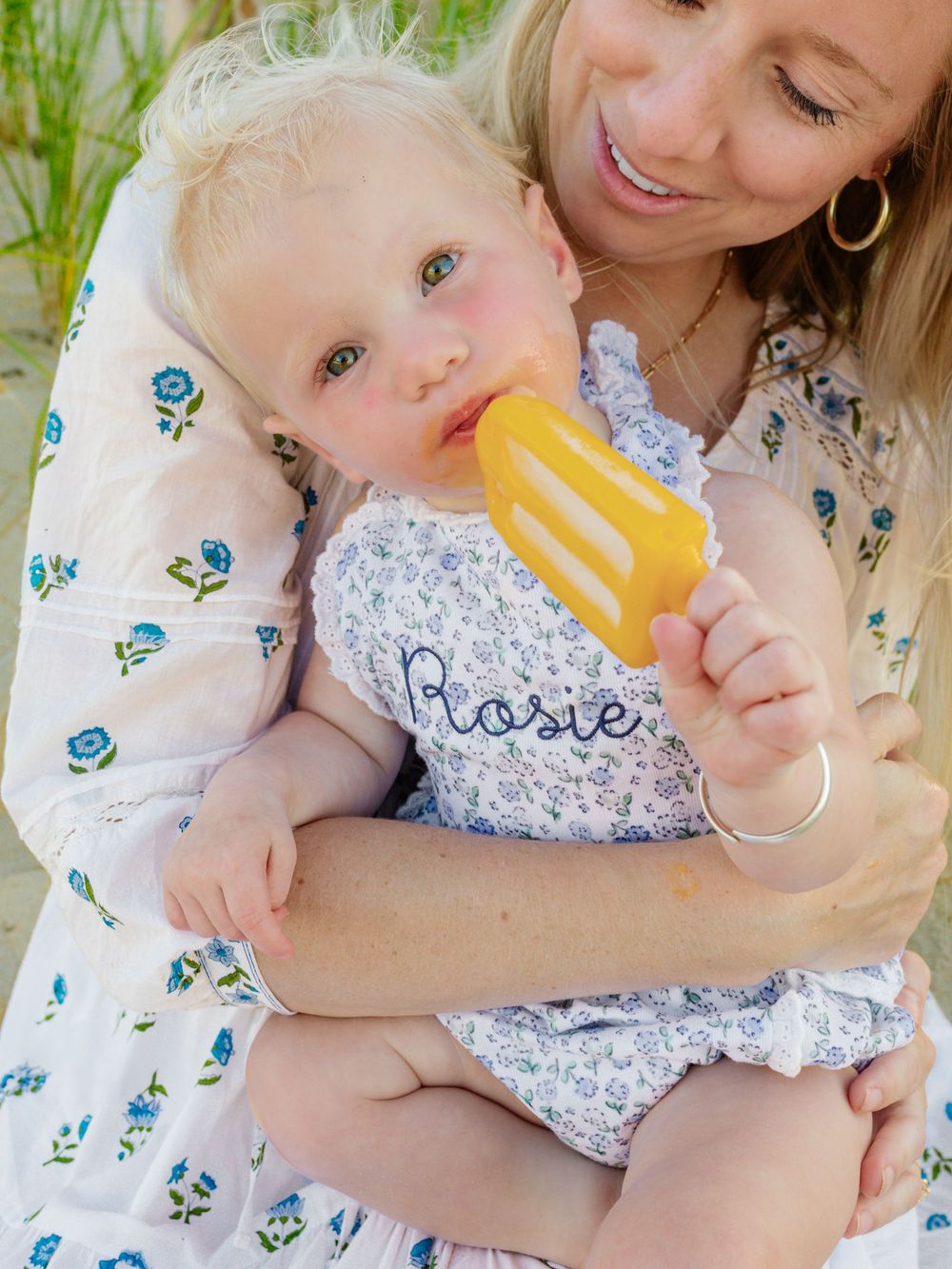 Mother and baby share sweet moment while baby drinks from bottle outdoors.