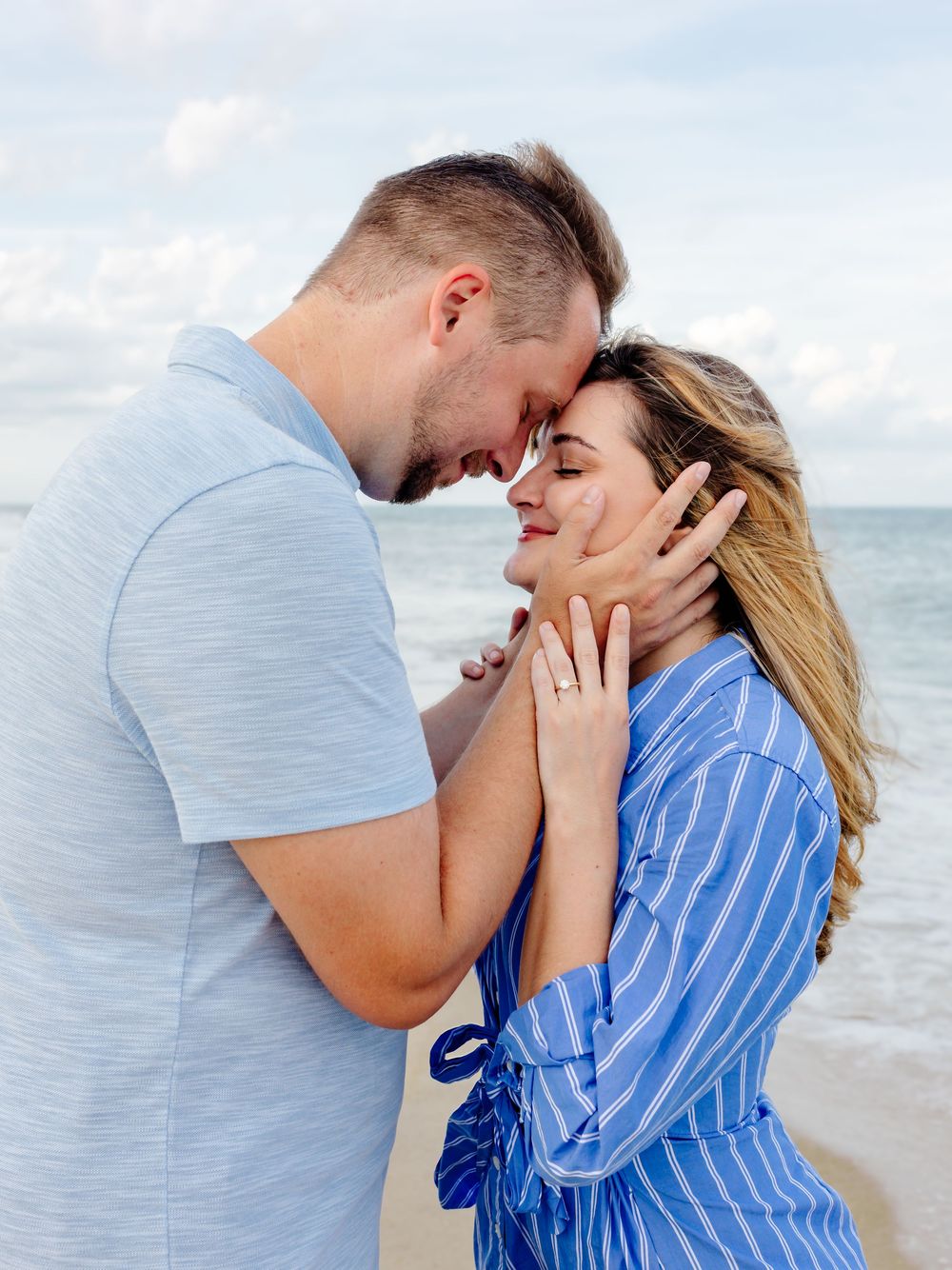 Romantic couple shares intimate moment on beach during sunset photoshoot.