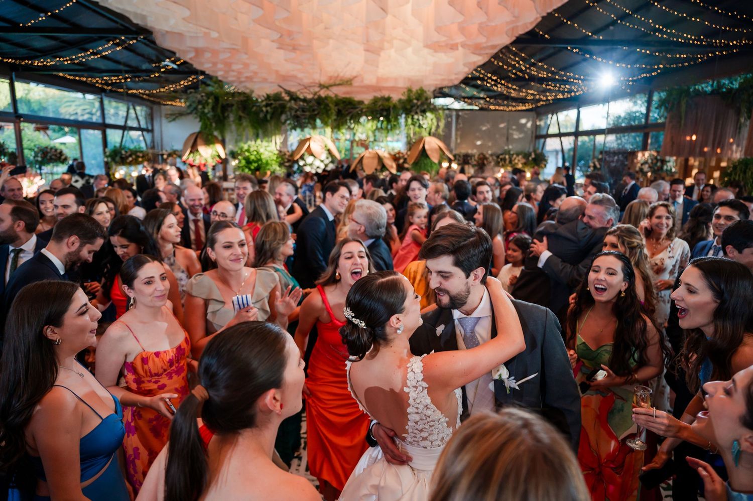 Lively wedding reception with crowd dancing and celebrating on a packed dance floor.