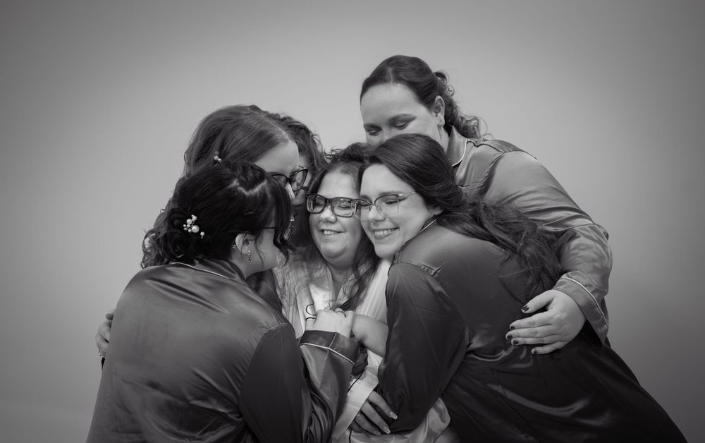 A black and white portrait of a group hugging together intimately in a close emotional moment.