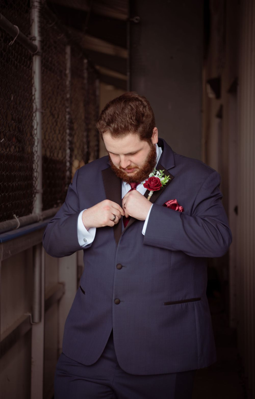 A groom in a navy suit with red boutonniere wipes tears from his eyes in an emotional sequence of photos.