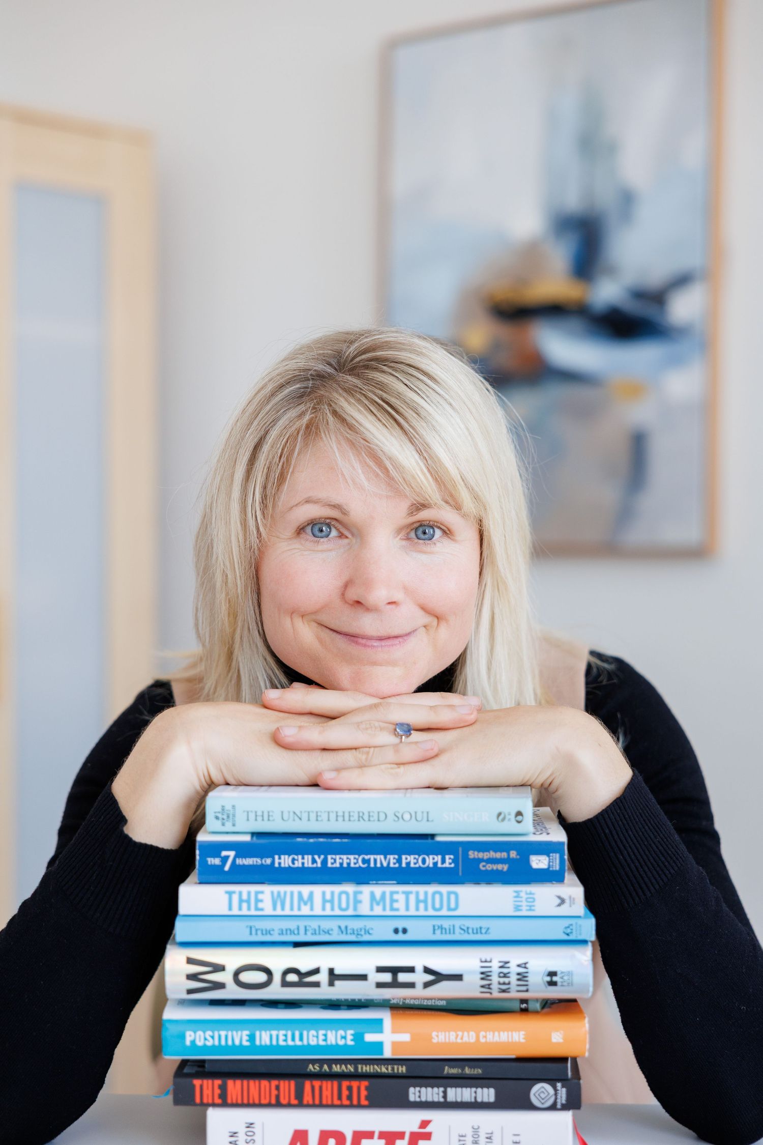 A person in black rests their head on a stack of self-help and personal development books in a creative photo series.