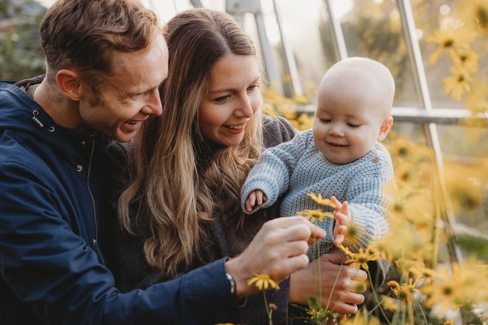 A happy family shares joyful moments together among yellow autumn flowers in golden sunlight.