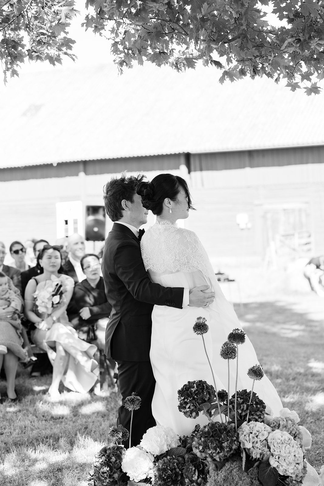 Black and white wedding photo series showing intimate moments between a couple in an outdoor garden setting with flowers.