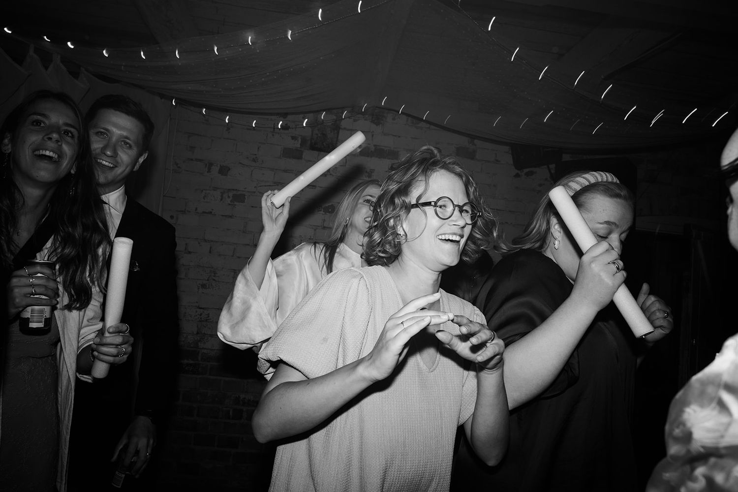 Black and white photo of a person drinking from a bottle at what appears to be a dimly lit bar or club setting.
