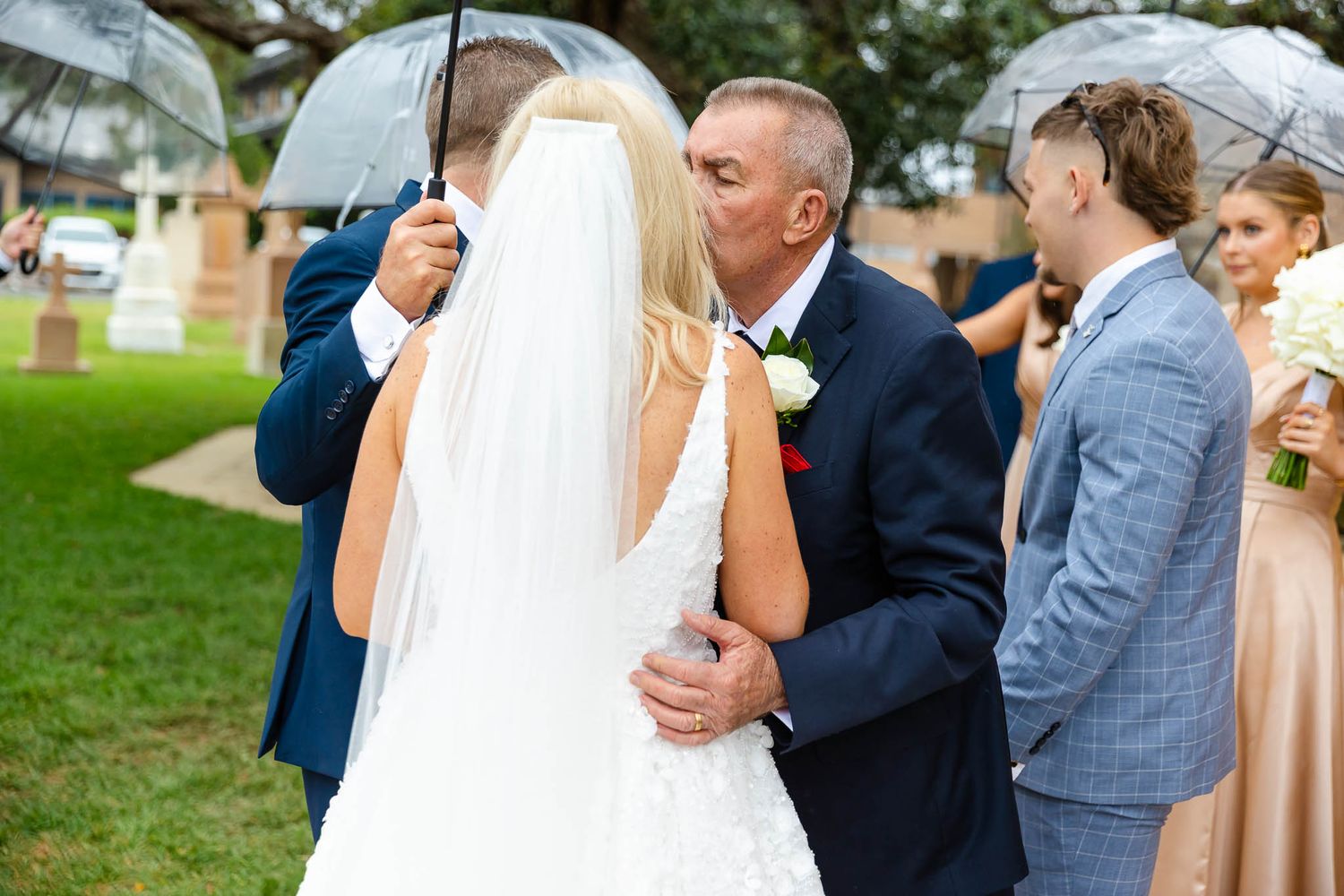 Wedding party members laughing and celebrating in front of a grassy outdoor venue.