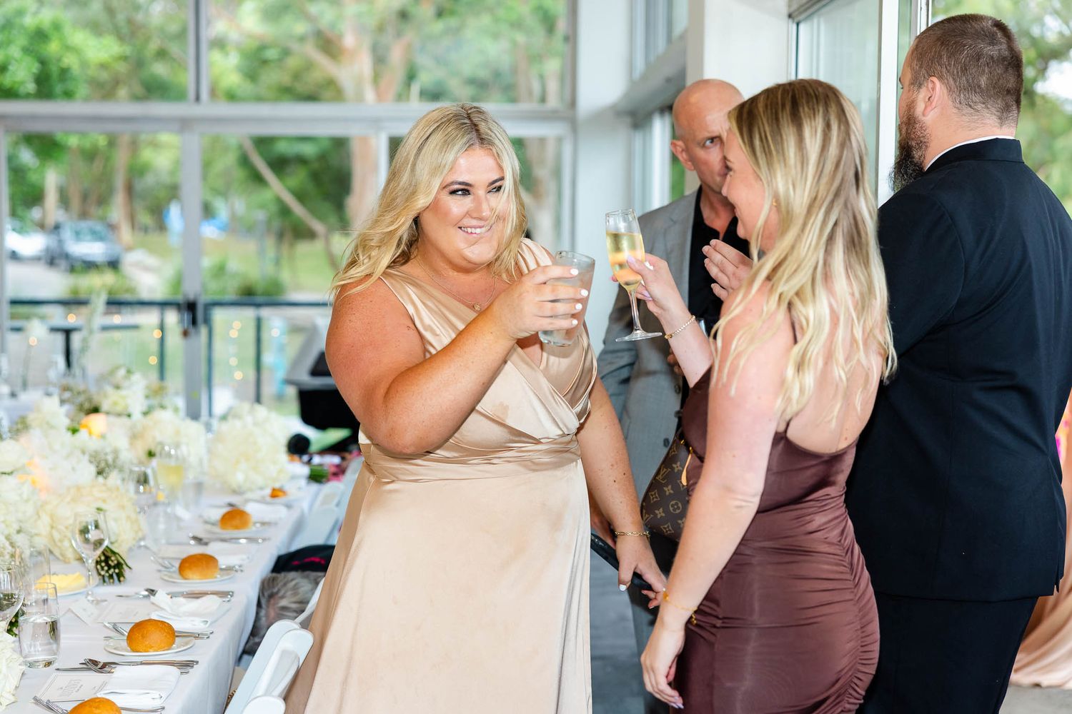 Guests enjoy drinks and conversation at an elegant event with a decorated buffet table.