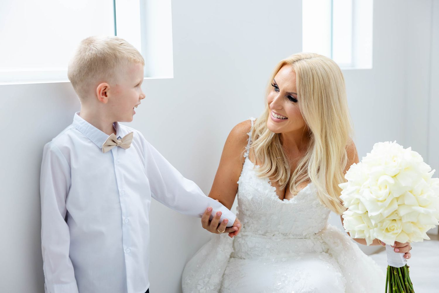 A series of five connected photos showing a tender moment between parent and child in an all-white room setting.