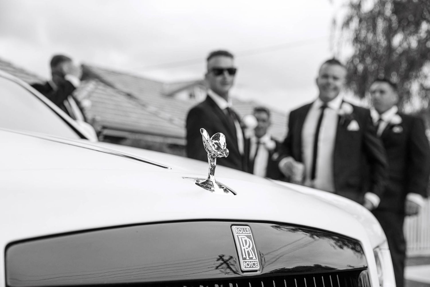 A classic black Rolls-Royce car is displayed at an outdoor event with spectators gathered around it.