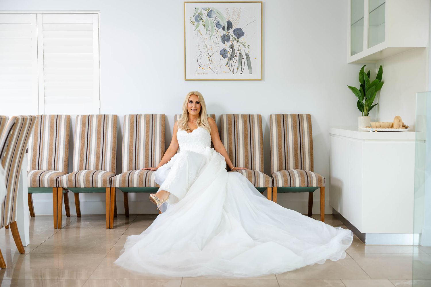 A bright white interior room decorated with framed artwork and striped upholstered chairs.