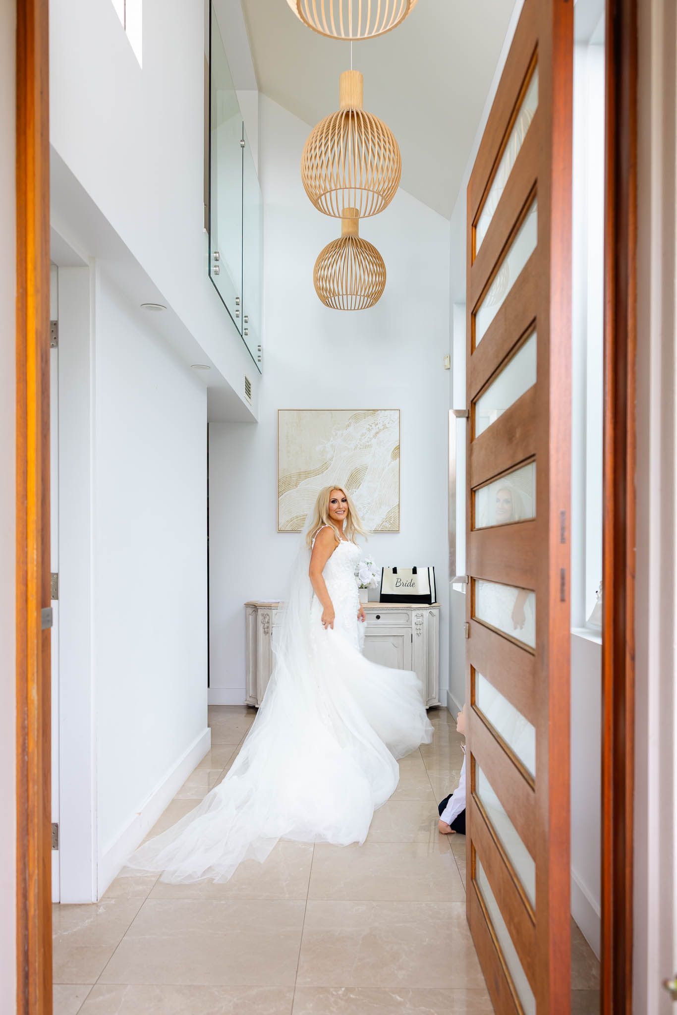 Modern hallway with hanging wicker pendant lights and wooden sliding door features elegant white wedding dress.