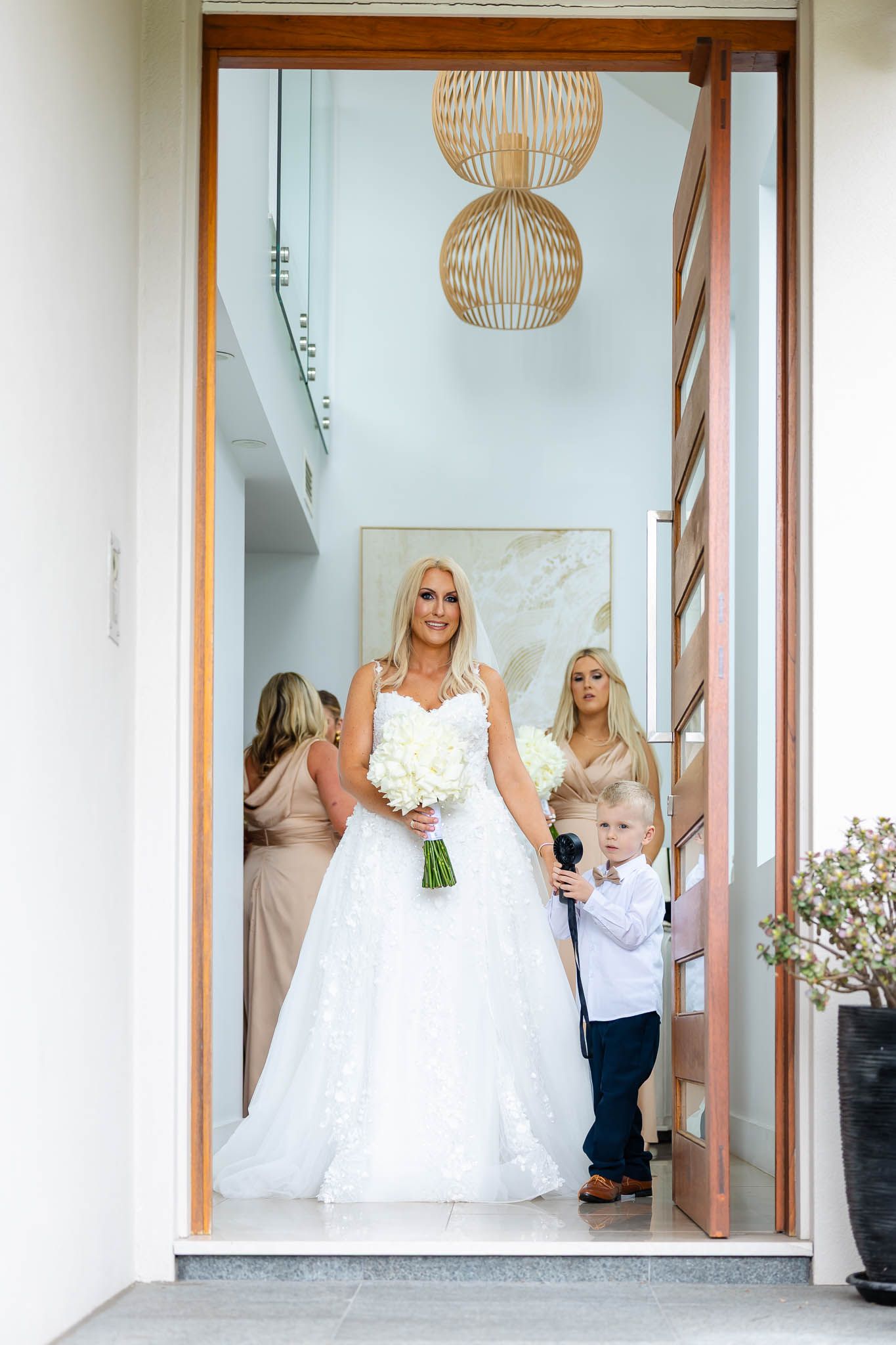 A bridal party getting ready in an elegant room with modern pendant lights and white decor.
