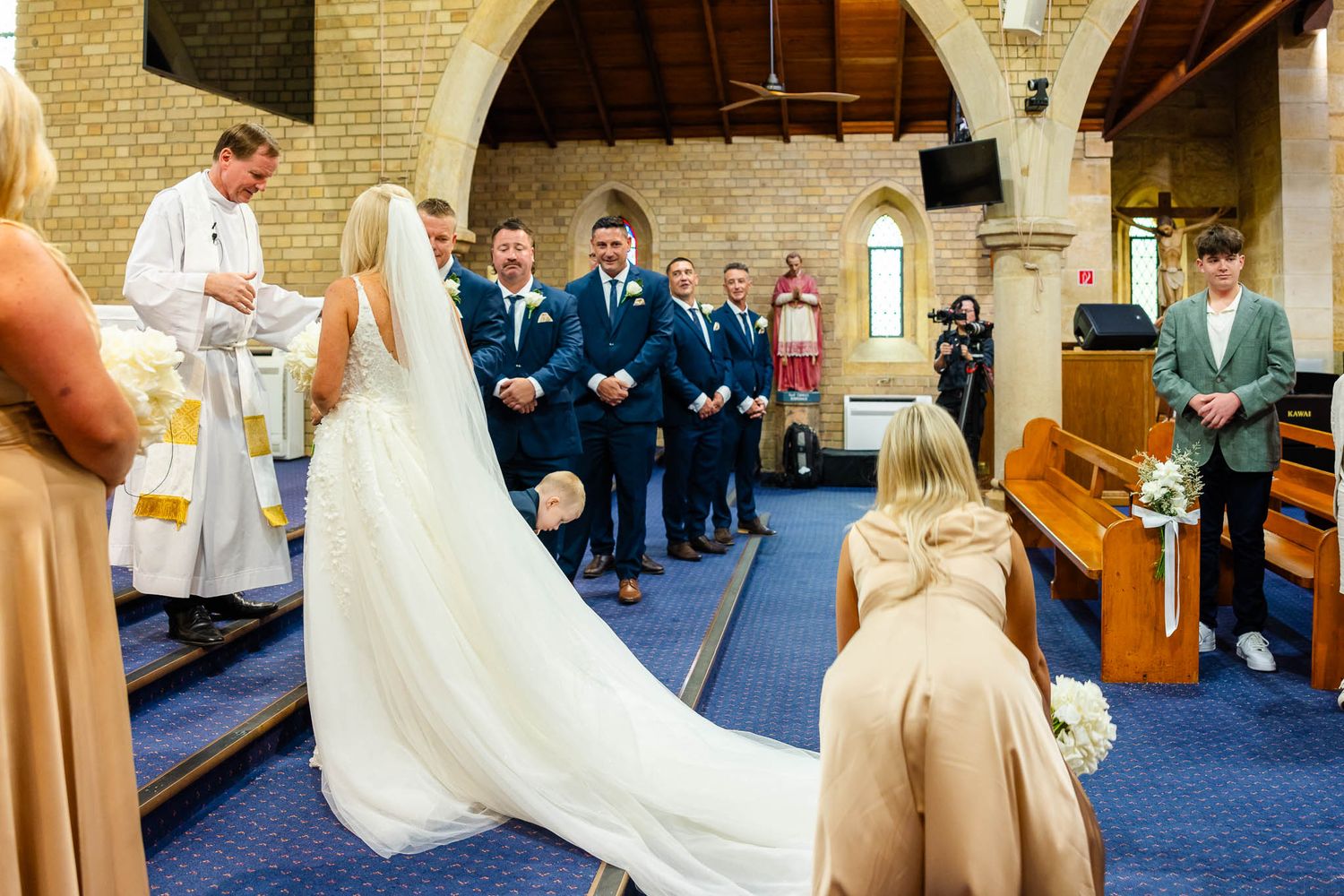 A traditional church wedding ceremony with a bride in a flowing white gown and veil standing at the altar with clergy.