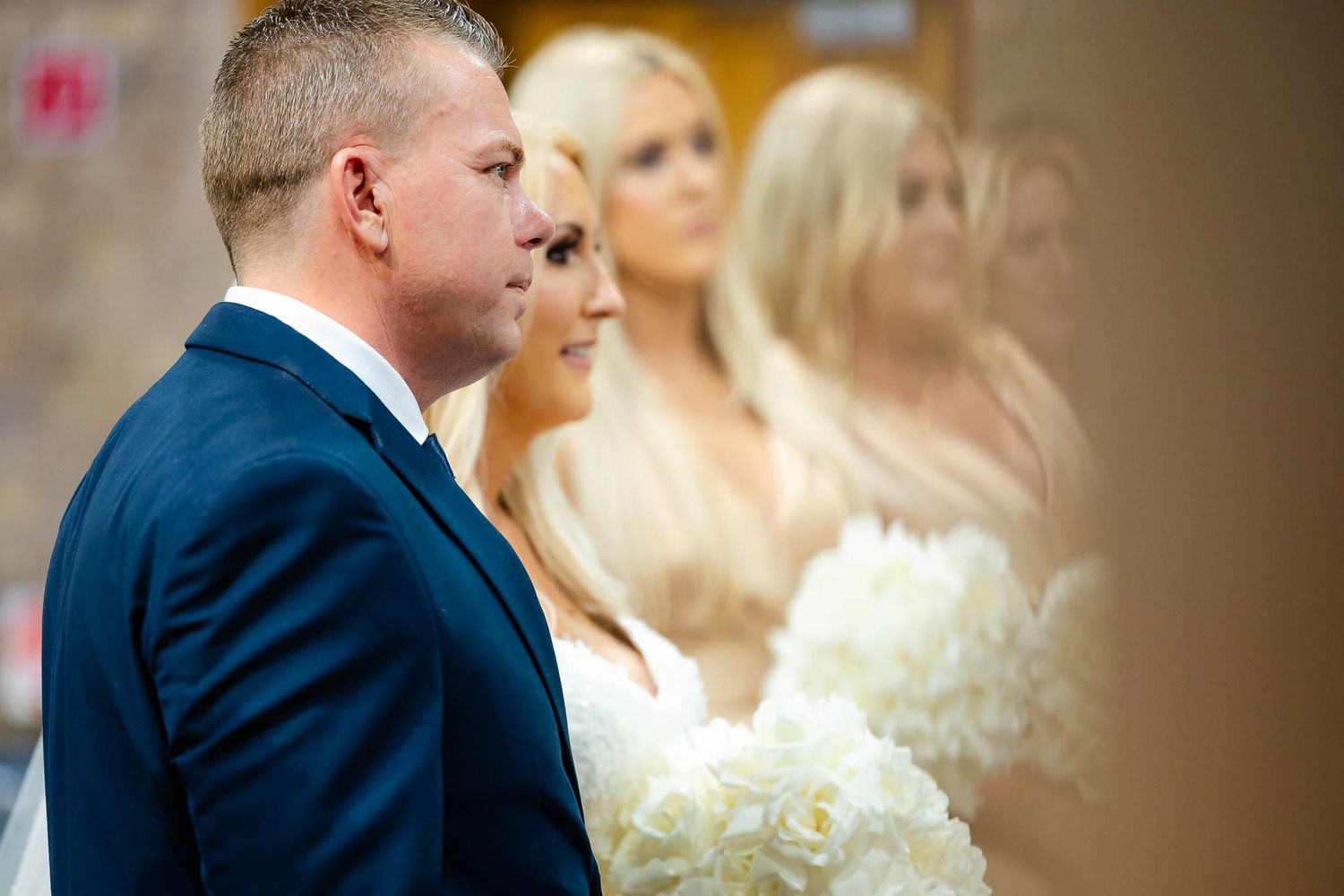 A wedding ceremony moment captured in a soft-lit church setting with elegant formal attire and traditional decor.