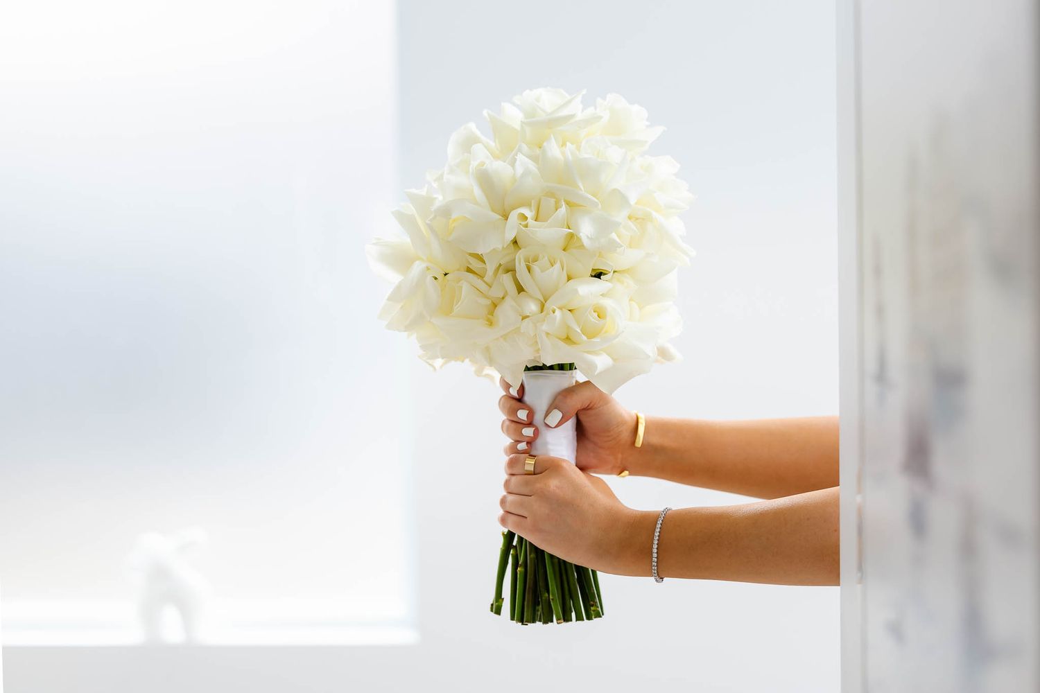 A delicate white hydrangea bouquet held against a soft blurry background.