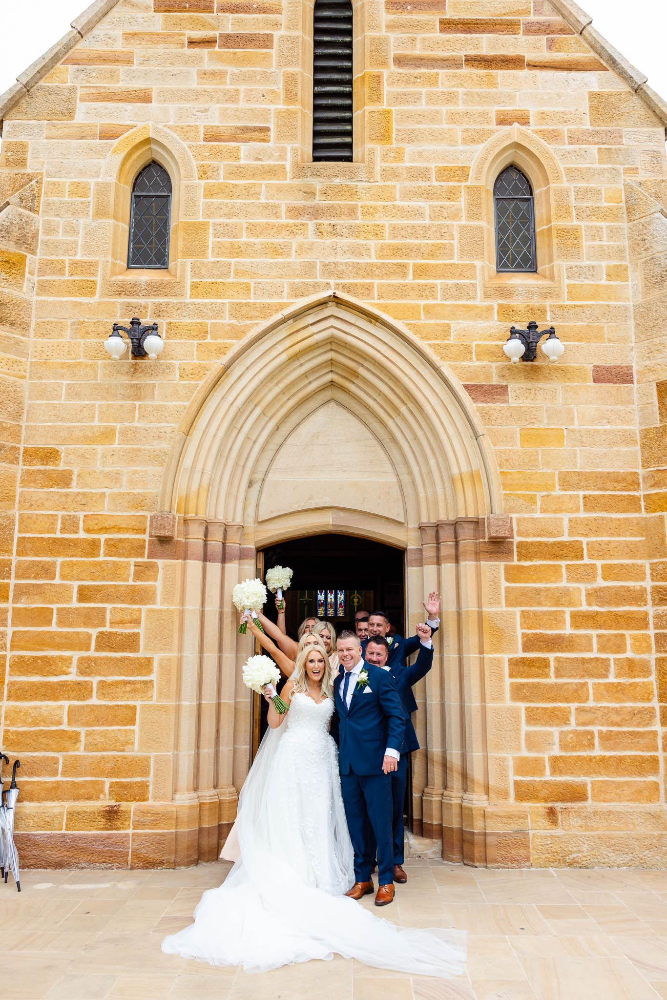 Three wedding photos showing couples posing in front of a sandstone church with gothic arched doorways.