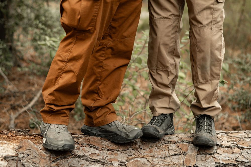 A close-up series of hiking boots and brown pants walking on a fallen tree trunk in the forest.