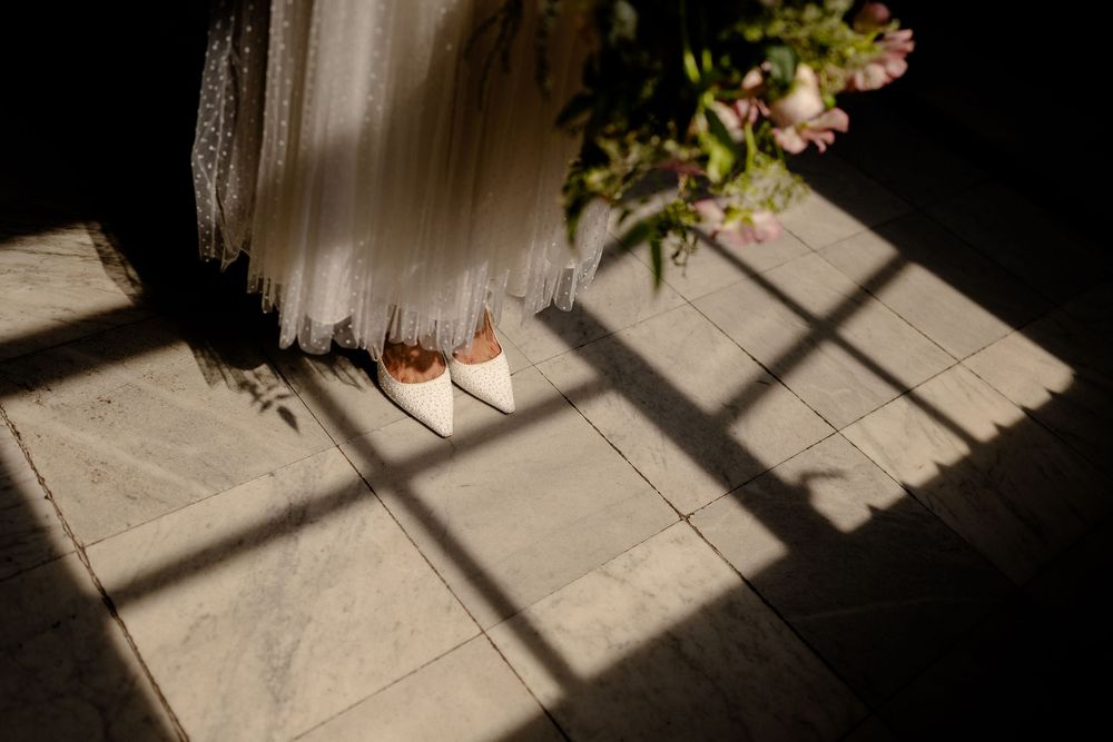 Dramatic shadows cast across a light colored floor with small plant detail visible.