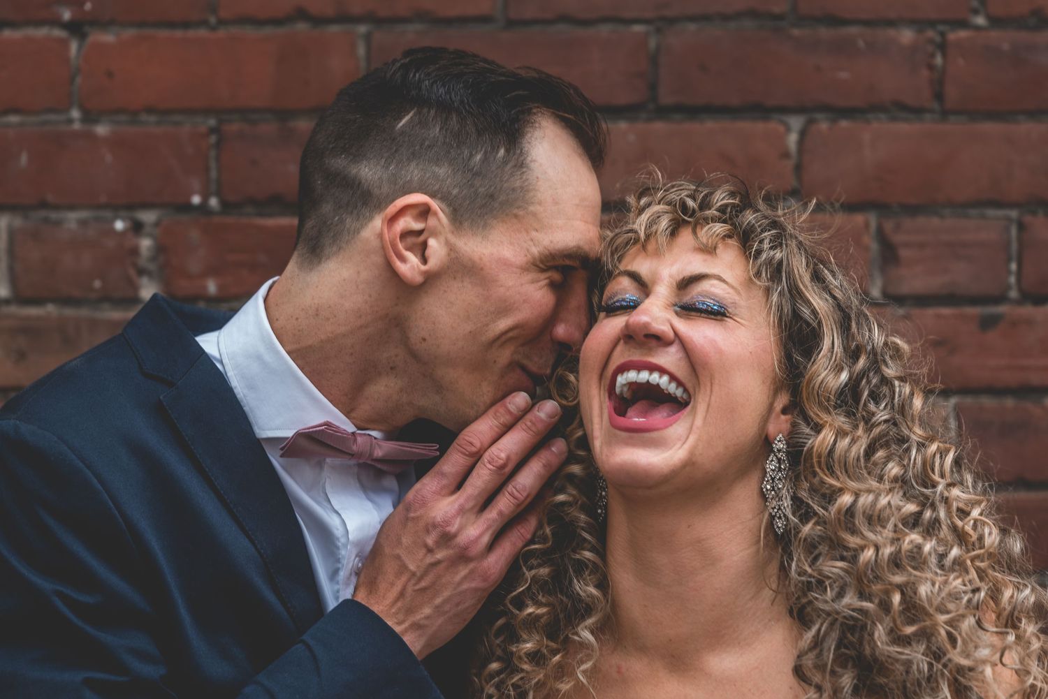Bride and groom laughing together during relaxed wedding portrait session.