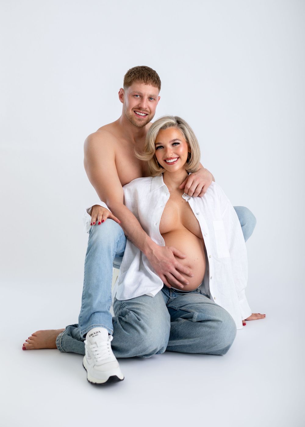 A couple wearing white tops and jeans poses casually on a white background in a series of connected photos.