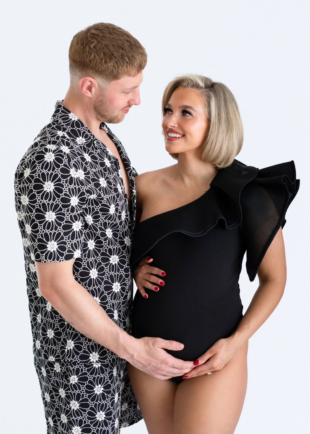 A couple in black and white floral attire poses together in three romantic dance-like positions.