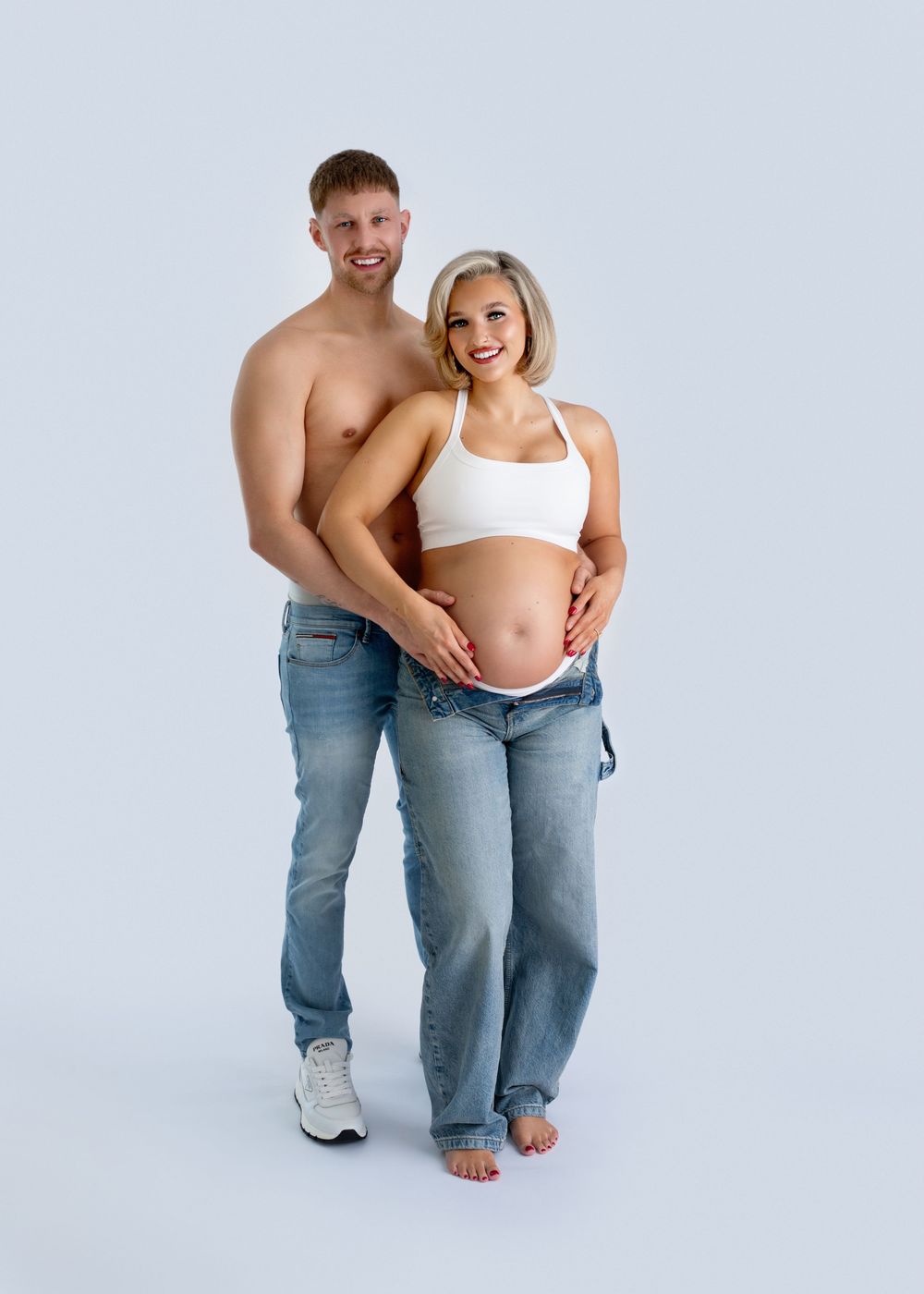 A couple in jeans share an intimate moment against a white backdrop showing progression of poses.