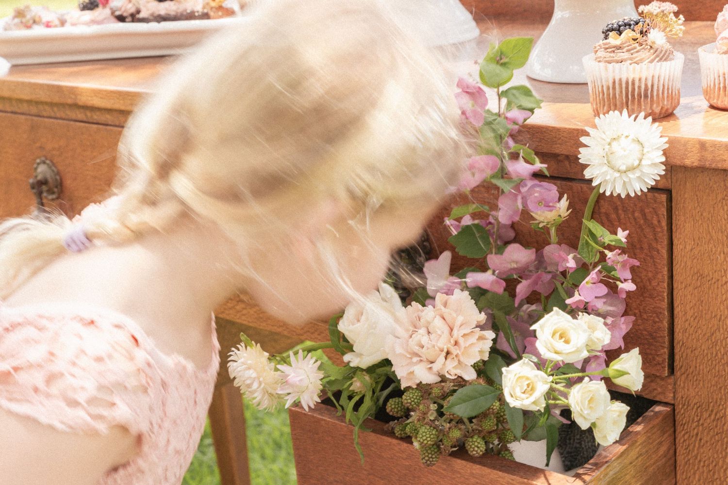 Floral arrangement with pink and white blooms cascading along wooden furniture.