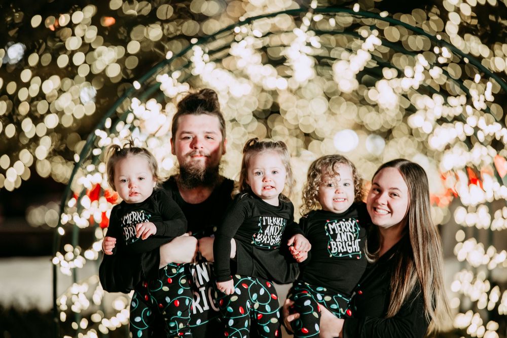 Family enjoying holiday photos outdoors with sparkling Christmas lights creating a magical bokeh backdrop.