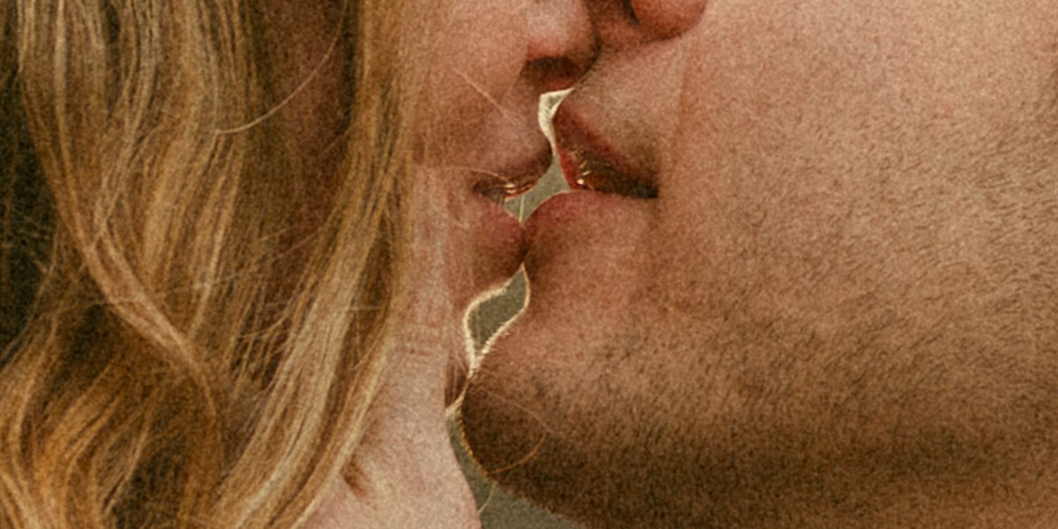 Close-up of a couple sharing a kiss, connected by a delicate gold chain jewelry piece between their lips.