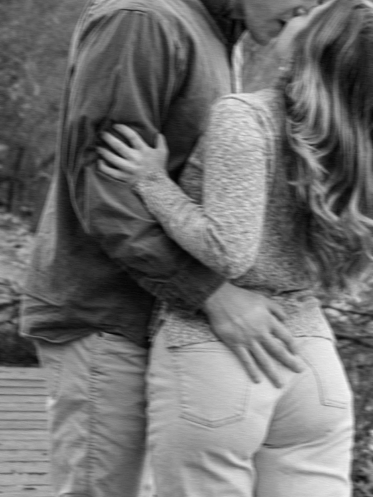 Black and white photo of a couple embracing and holding each other close outdoors.