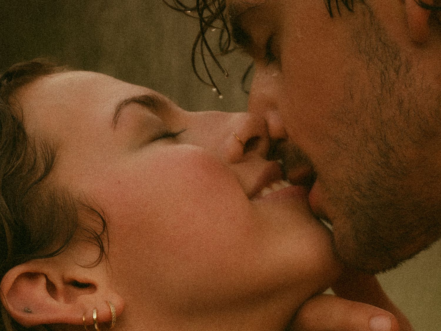 A romantic couple sharing a passionate kiss, with wet hair suggesting an intimate moment in the rain.