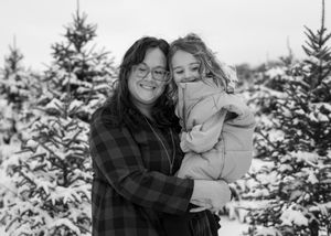 Black and white winter portraits showing tender moments against a snowy forest backdrop.