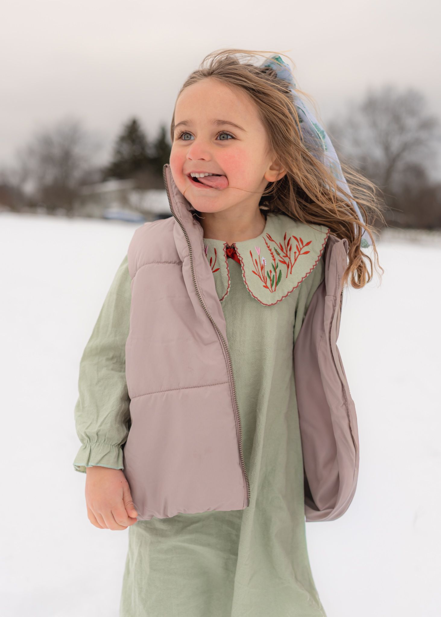 A series of joyful winter portraits showing someone in a pink vest and mint green top playing in the snow.