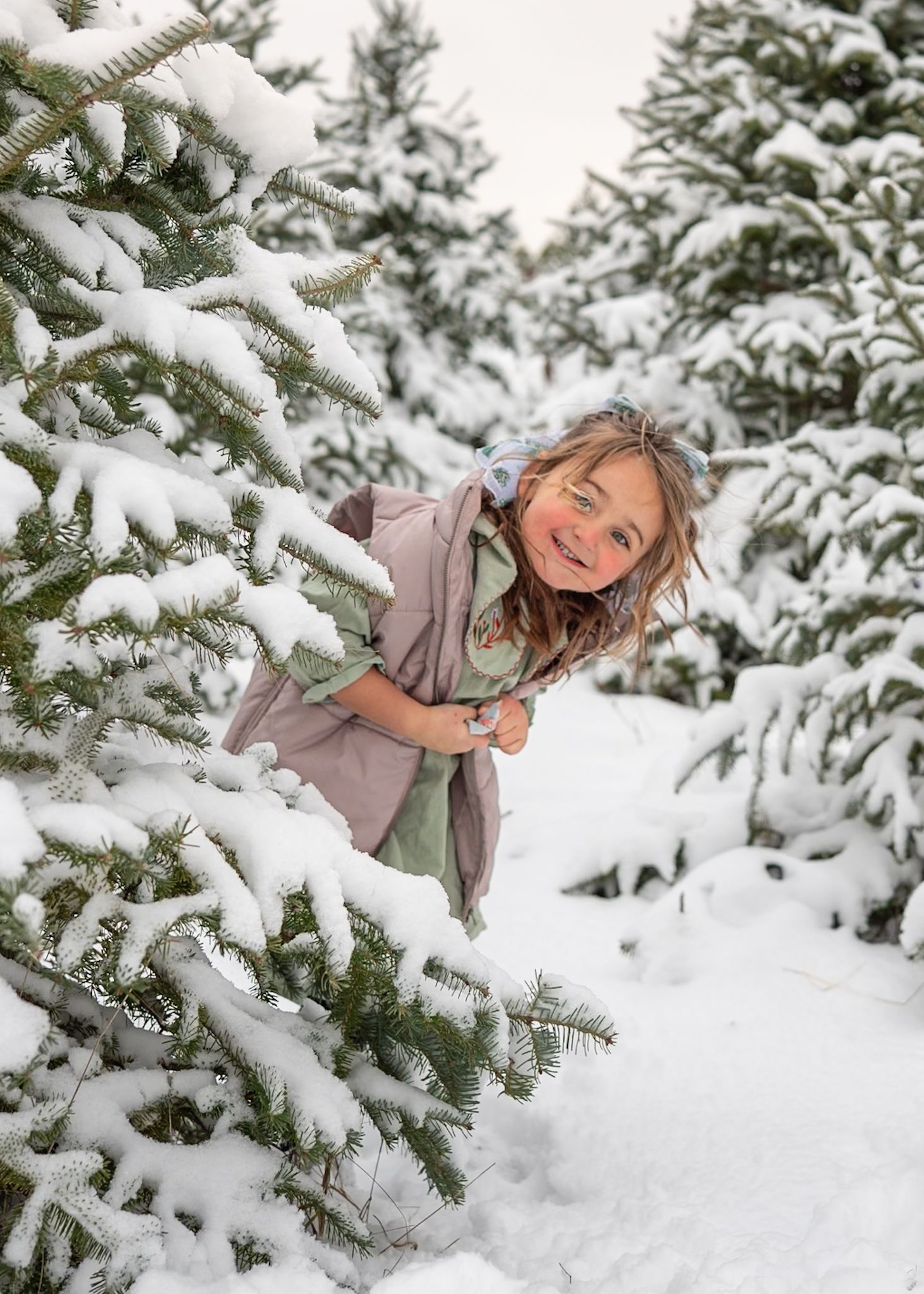 Playful winter moments captured in the snow among snow-covered evergreen trees.