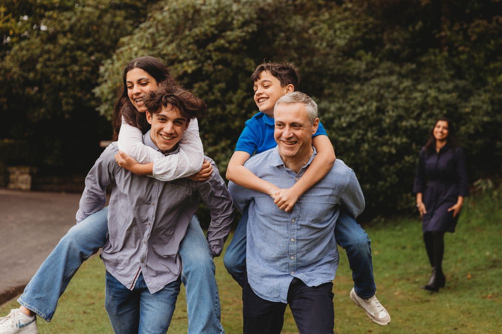 Group of people enjoying playful moments together outdoors in a park setting on a sunny day.