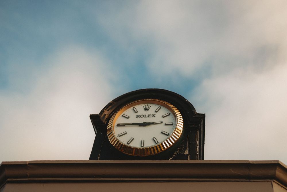 A row of vintage clocks mounted on a wall showing different times throughout the day.
