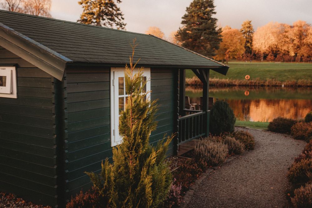 Rustic dark green cabins nestled among autumn trees at sunset with a gravel path leading between them.