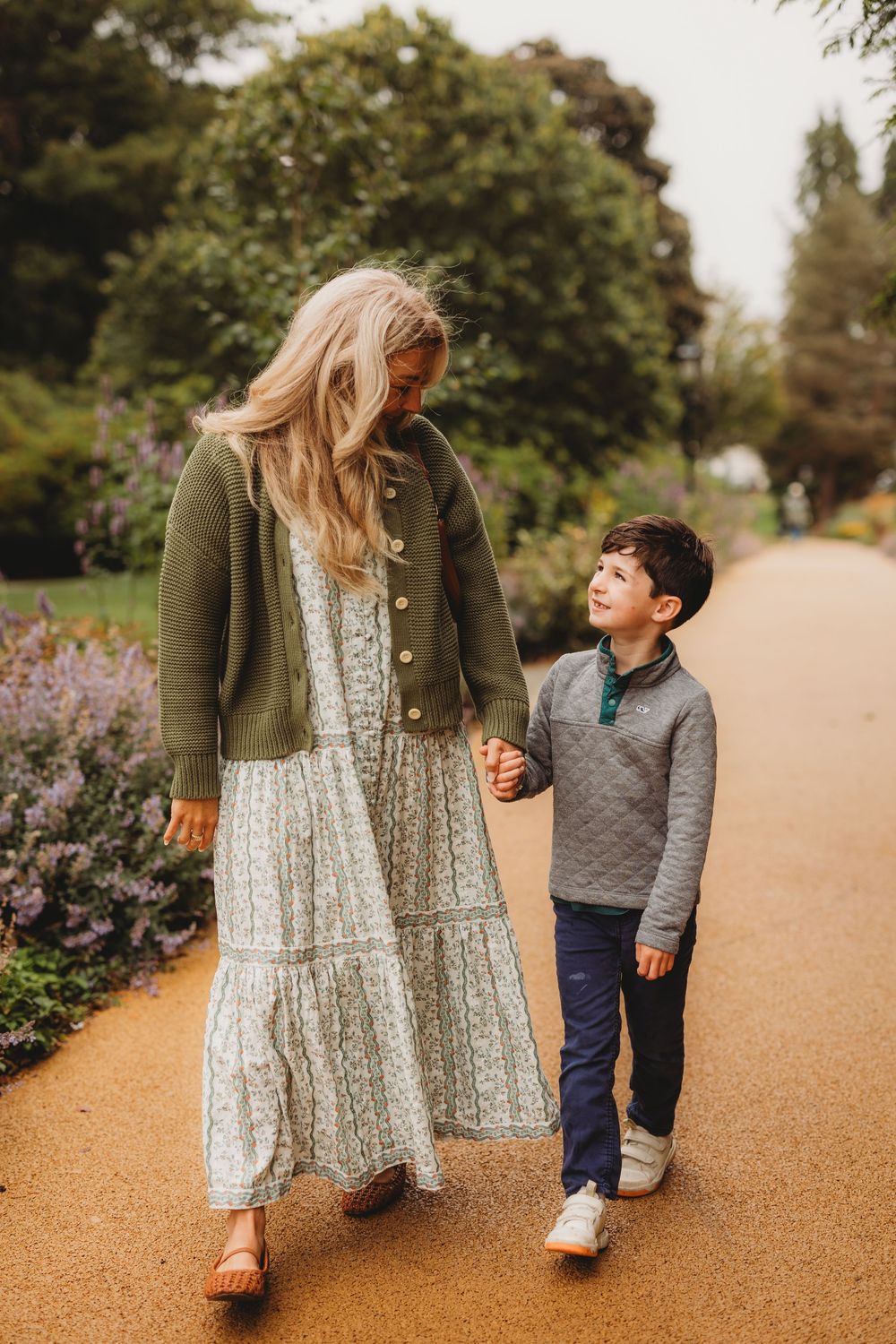A heartwarming scene of a parent and child walking together on a path with flowers blooming nearby.
